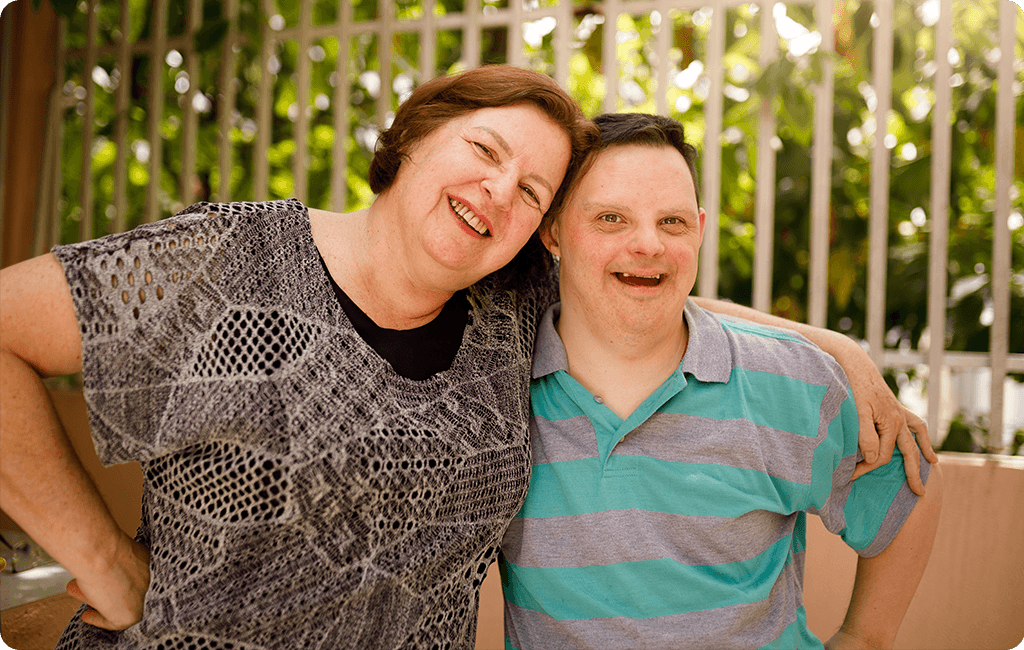 Photo of a middle aged woman with arm around man with intellectual impairment