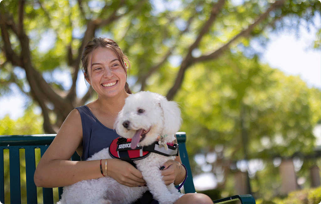 Woman sitting on a park bench with her assistance dog.