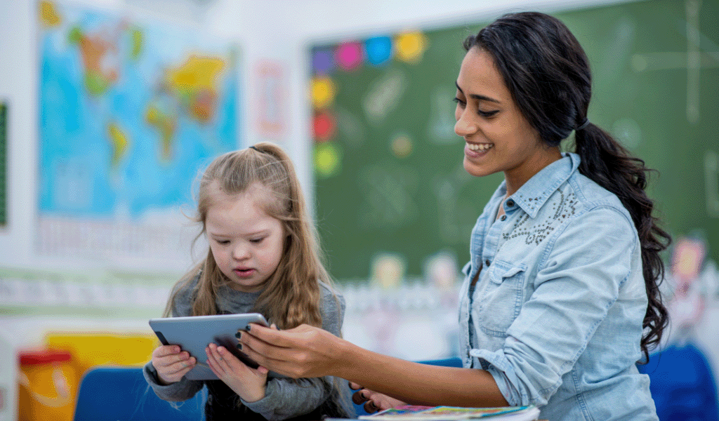 Teacher helping young girl with disability on a tablet
