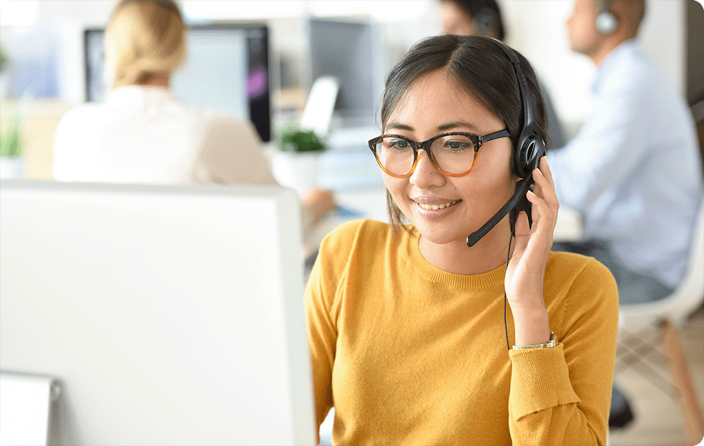 Young woman in a bright office wearing a headset and talking to someone on the phone