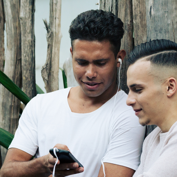 Two young men in white t-shirts looking at the same phone screen
