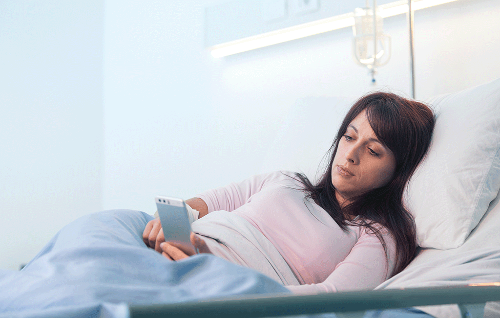Woman in hospital bed scrolling on her phone